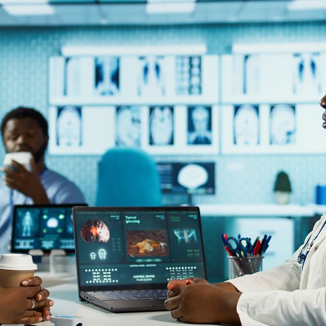 A clinician and a patient reviewing scan results together on a laptop.