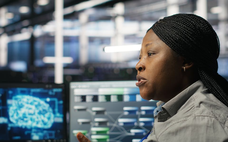 An engineer working at a monitoring console inside a server hall.