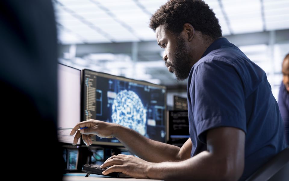 A data scientist tracing a model's output across two monitors.